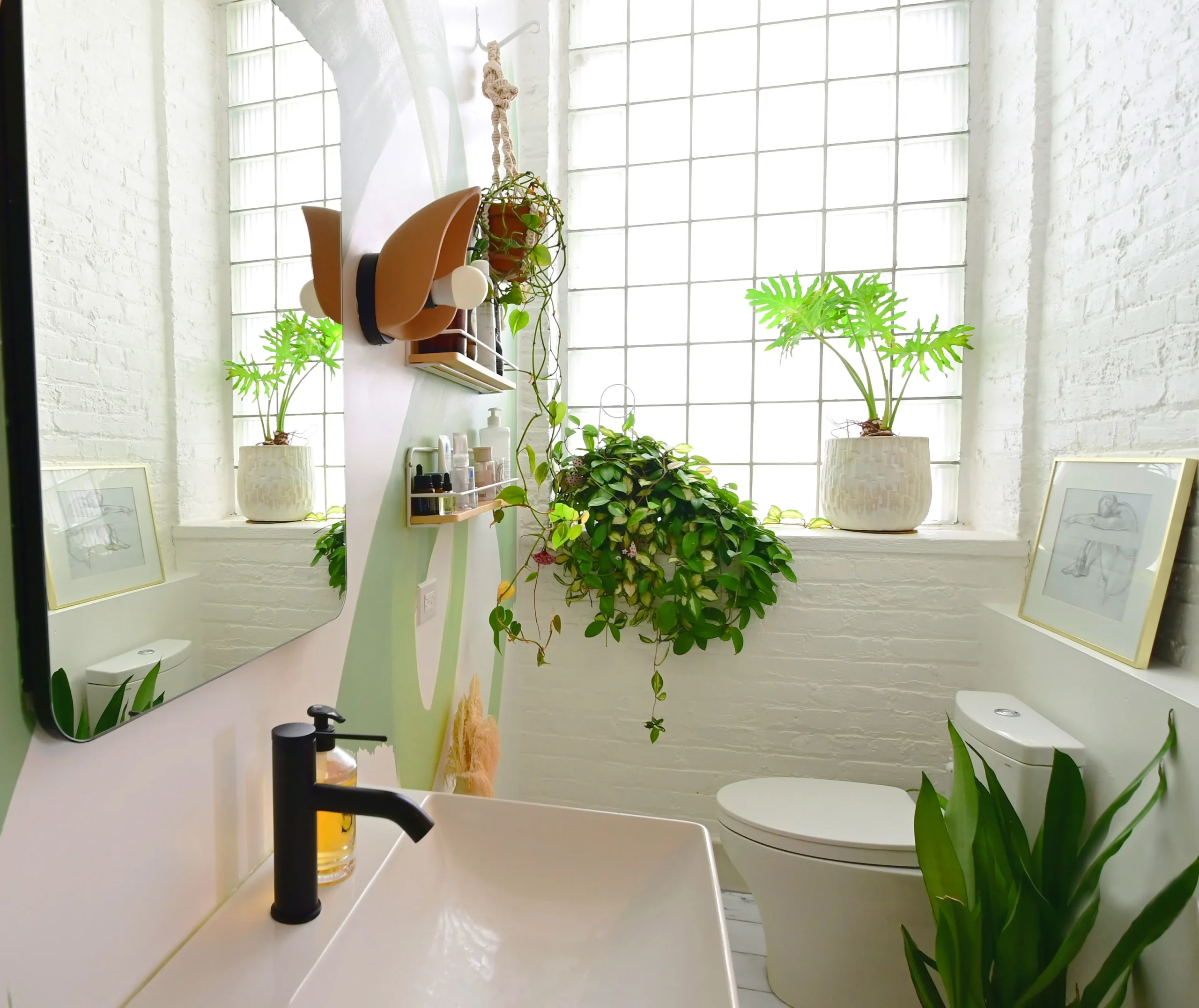 A tastefully decorated bathroom featuring lush green plants, and a large window with natural light streaming in. Chicago Loft project styled and designed by Laure Leger Studio